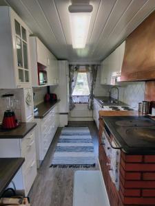 Villa Kotiranta في يامسا: مطبخ مع خزائن بيضاء وسجادة على الأرض