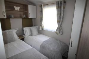 Habitación pequeña con 2 camas y ventana en The One - Chalet in the Cairngorms en Boat of Garten