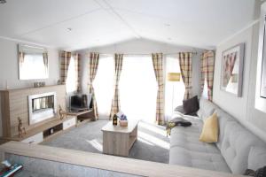 a living room with a couch and a tv at The One - Chalet in the Cairngorms in Boat of Garten