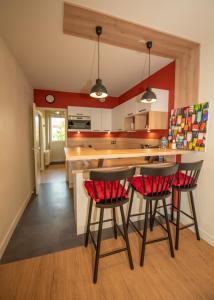 a kitchen with red walls and a counter with chairs at La Villa du Sillon in Saint Malo