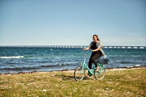 a woman is riding a bike on the beach at Storebælt Sinatur Hotel & Konference in Nyborg