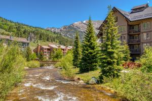 a river in front of a resort with a mountain at Copper Springs 426 in Frisco