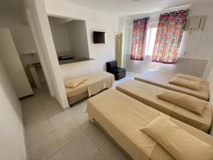 Habitación de hotel con 3 camas y TV en Pousada Morada das Nações en Balneario Camboriú