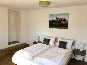 Bilderbuchcafe - Ferien Apartment NO 5 - Markt 7 في هافلبرغ: سرير أبيض في غرفة بيضاء فيها مصباحين