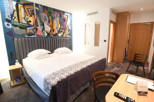 a hotel room with a bed and a desk and a table at Hotel Aida Opera in Paris