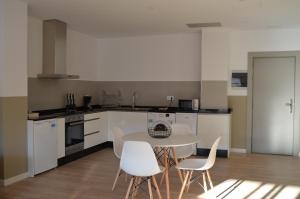 a kitchen with a table and white chairs in a room at Hotel Airiños 3* in Cangas de Morrazo