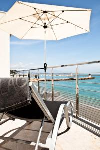 a chair with an umbrella on a balcony overlooking the ocean at Villa Azur in Villeneuve-Loubet