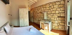 a bedroom with a stone wall with a bed and a sink at Oberj d'Azur Alaçatı in Alaçatı
