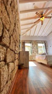 a bedroom with a stone wall with a bed and a ceiling fan at Oberj d'Azur Alaçatı in Alaçatı