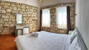 a bedroom with a stone wall and a bed with towels at Oberj d'Azur Alaçatı in Alaçatı