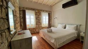 a bedroom with a bed and a stone wall at Oberj d'Azur Alaçatı in Alaçatı