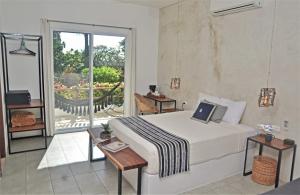 a hotel room with a bed, table and a window at Hotel Aires Bacalar in Bacalar
