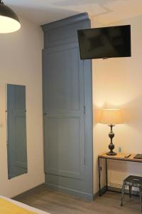 a room with a wall with a tv and a desk at Logis Hôtel Restaurant La Brasserie in Treignac