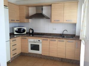 eine Küche mit Holzschränken, einer Spüle und einer Mikrowelle in der Unterkunft Apartment Ronda City Center in Ronda