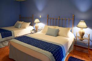 a bedroom with two beds with blue walls and lamps at Finca Hotel Los Girasoles in Montenegro