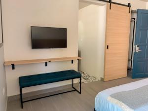 1 dormitorio con TV en la pared y 1 cama en The Ivy Hotel en San Juan