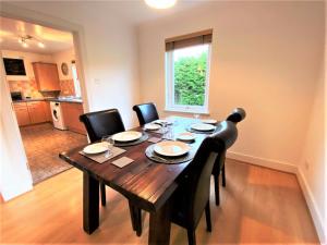 a dining room table with black chairs and a kitchen at Grampian Serviced Apartments - Garden Neuk - Lesmurdie House in Elgin