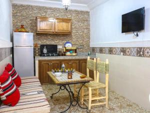 a small kitchen with a table and a refrigerator at Dar Habache in Marrakesh