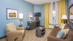 uma sala de estar com um sofá e cadeiras num quarto de hotel em Candlewood Suites Sidney, an IHG Hotel em Sidney