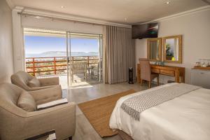 a bedroom with a bed and a desk and a balcony at Belle Vue Ridge BnB, in Plettenberg Bay