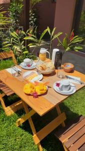 una mesa de picnic de madera con comida y bebidas. en Hospedaria Oitis, en Búzios