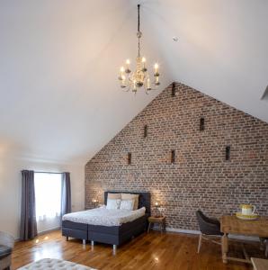 a bedroom with a brick wall with a bed and a chandelier at B&B De Bloesem in Hoeselt