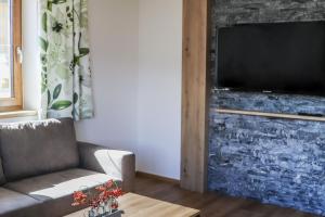 a living room with a couch and a television on a brick wall at Klausenstein Gutshof Hollersbach in Hollersbach im Pinzgau