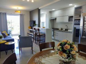 cocina y sala de estar con mesa y sillas en Apartamento Ipê Branco, Mariscal, ótima localização, en Bombinhas