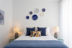 a bedroom with a bed with blue pillows and plates on the wall at STUPENDO- Two Rooms, patio With refreshing Pond-Center-Air conditioning in Lisbon +55 photos
