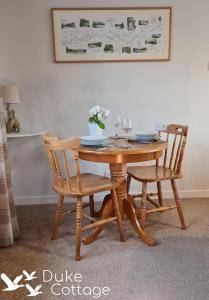 drewniany stół z 2 krzesłami i wazon kwiatów w obiekcie Duke Cottage w mieście Fochabers
