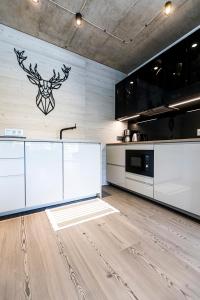 a kitchen with white cabinets and a wall with a deer head on it at Mountain View Apartament 1 in Szczyrk