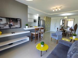 sala de estar con sofá y TV y cocina en Apartamento Ipê Branco, Mariscal, ótima localização, en Bombinhas