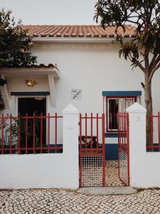 une clôture rouge devant une maison blanche dans l'établissement Maria Tereza Sea Villa, à Costa da Caparica