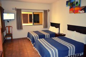 a hotel room with two beds and a flat screen tv at Hotel Don Nino in Oaxaca City
