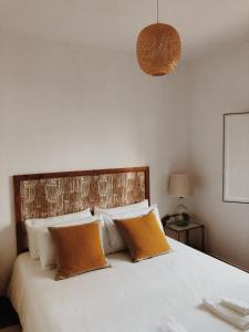 sypialnia z dużym białym łóżkiem z pomarańczowymi poduszkami w obiekcie Maria Tereza Sea Villa w Costa de Caparica