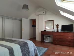 a bedroom with a bed and a dresser with a television at Penthouse Marina Sol in Madalena do Mar