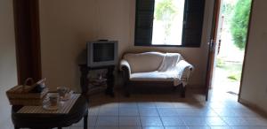 a living room with a white chair and a television at Chalé e Camping Daragona 1 in Águas de Lindóia