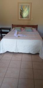 um quarto com uma cama grande e lençóis brancos em Chalé e Camping Daragona 1 em Águas de Lindoia
