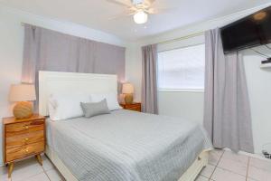 um quarto com uma cama, uma janela e uma televisão em Binnie’s Beachfront Bungalow em Clearwater Beach