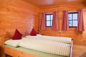 2 Betten in einem Blockhaus mit Fenstern in der Unterkunft Appartement Rossalm mit Sauna in Alpbach