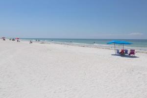 two chairs and an umbrella on a beach at 104 Hamilton House in Clearwater Beach