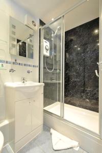 a white bathroom with a shower and a sink at The Old Bridge House in Looe