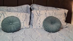 two green pillows on a bed with white sheets at Spacious 3 Bedroom House, 6 beds in Spondon, Derby with Parking in Derby