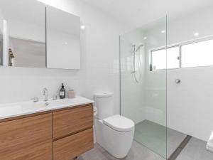 a white bathroom with a toilet and a shower at Mobys at Hyams Beach in Hyams Beach +12 photos