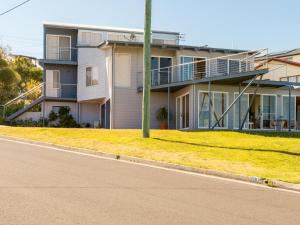 a apartment building with a porch and a street at Alexandra Suite Gerroa in Gerroa