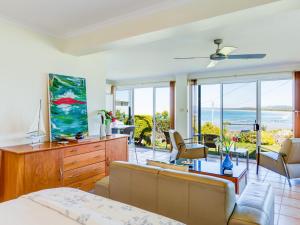 a bedroom with a living room with a view of the ocean at Alexandra Suite Gerroa in Gerroa