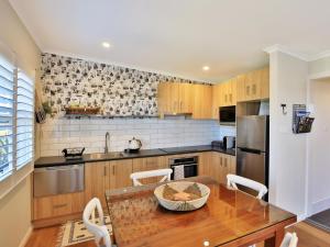 a kitchen with a table and chairs and a refrigerator at Jervis Bay Beach Shack I Pet Friendly in Vincentia