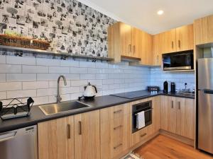 a kitchen with wooden cabinets and stainless steel appliances at Jervis Bay Beach Shack I Pet Friendly in Vincentia