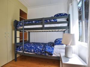 a bedroom with two bunk beds with blue and white sheets at Nest I Pet Friendly I 2 Min Walk to Beach in Currarong