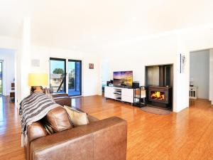 a person sitting on a couch in a living room with a fireplace at The Palings at Culburra I Pet Friendly Masterpiece in Culburra Beach